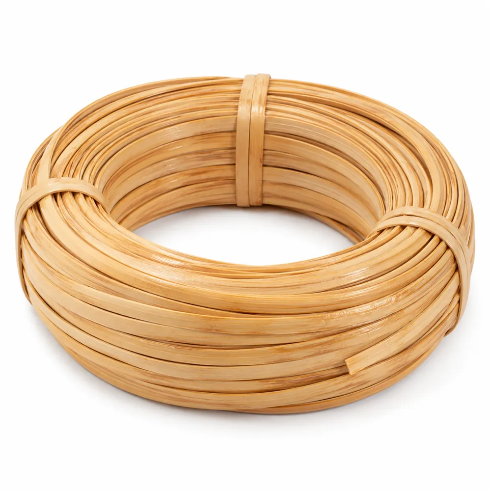 Neat coil of wide, flat, glossy honey-blond binder cane, tied, on a white background