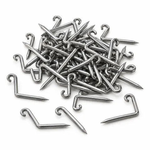 Small pile of L-shaped steel nails with bent loop ends, a few lying apart, on a white background