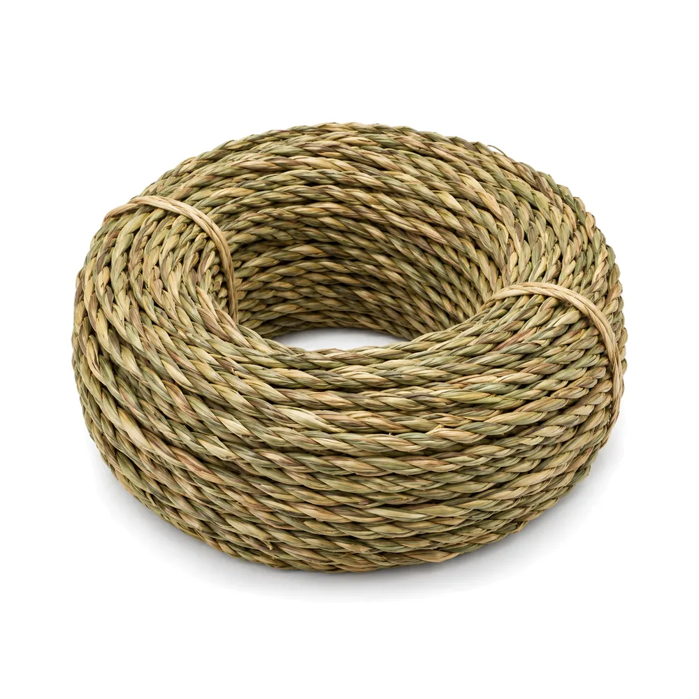 Large coil of twisted natural seagrass rush in green-to-wheat tones on a white background