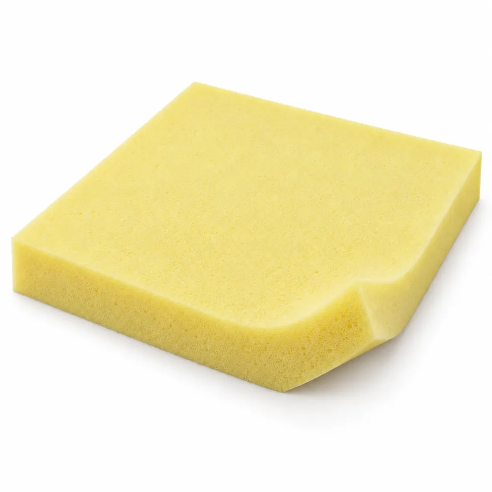 Square slab of pale yellow 2 in upholstery foam with one corner lifted to show its thickness, on a white background