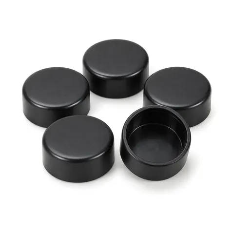 Group of round black plastic patio chair feet caps, one turned over to show the inside, on a white background