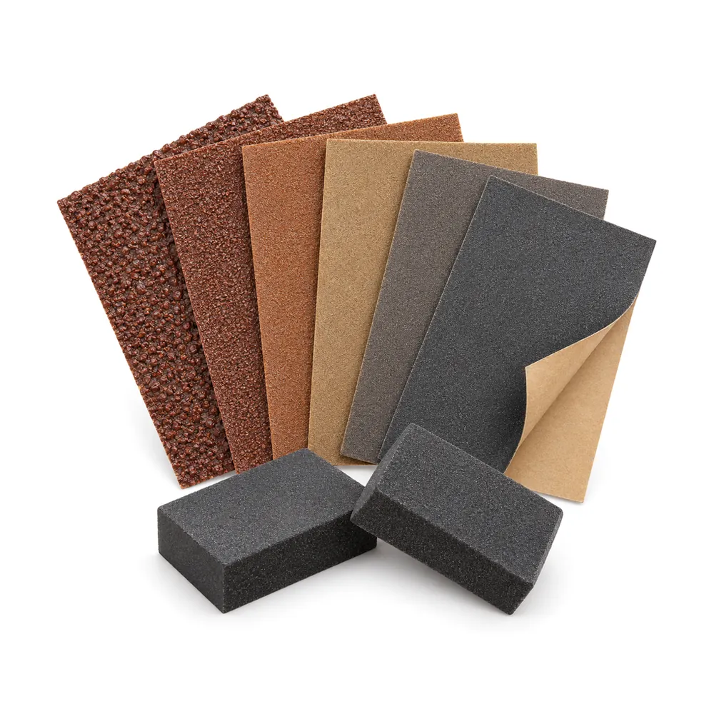 Fanned sandpaper sheets from coarse to fine with two small finger sanding blocks, on a white background